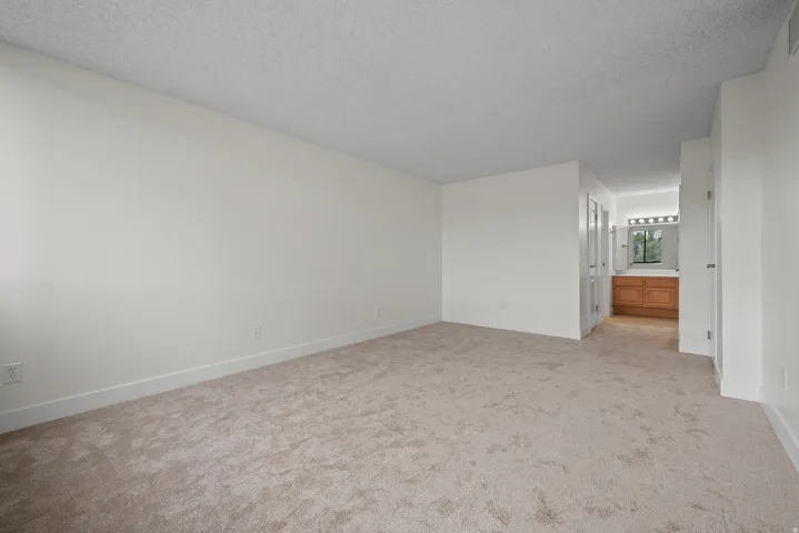 Neutral-toned carpeting, white walls, and a built-in vanity with a mirror and overhead lighting