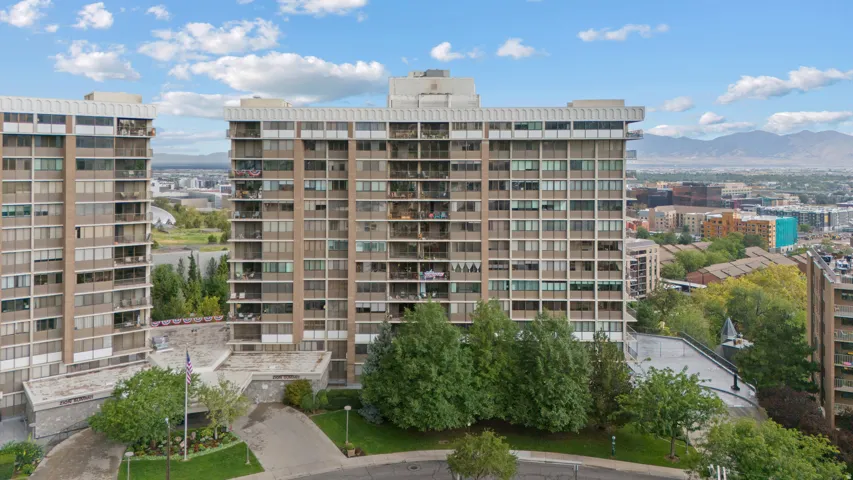 High-rise residential building featuring multiple balconies, a structured facade, and surrounding green landscaping