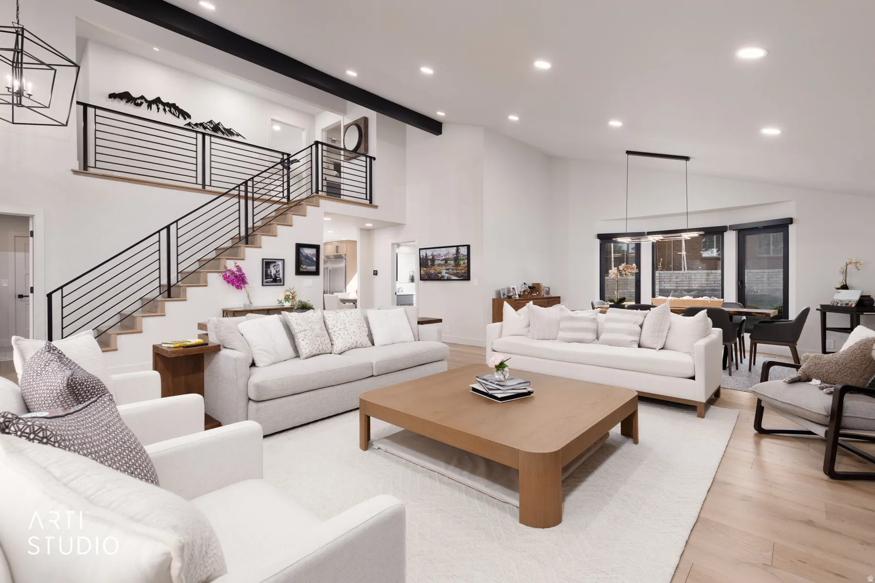 Open-concept living space featuring high ceilings, wood-finish flooring, a modern staircase with black railings, recessed lighting, and large windows