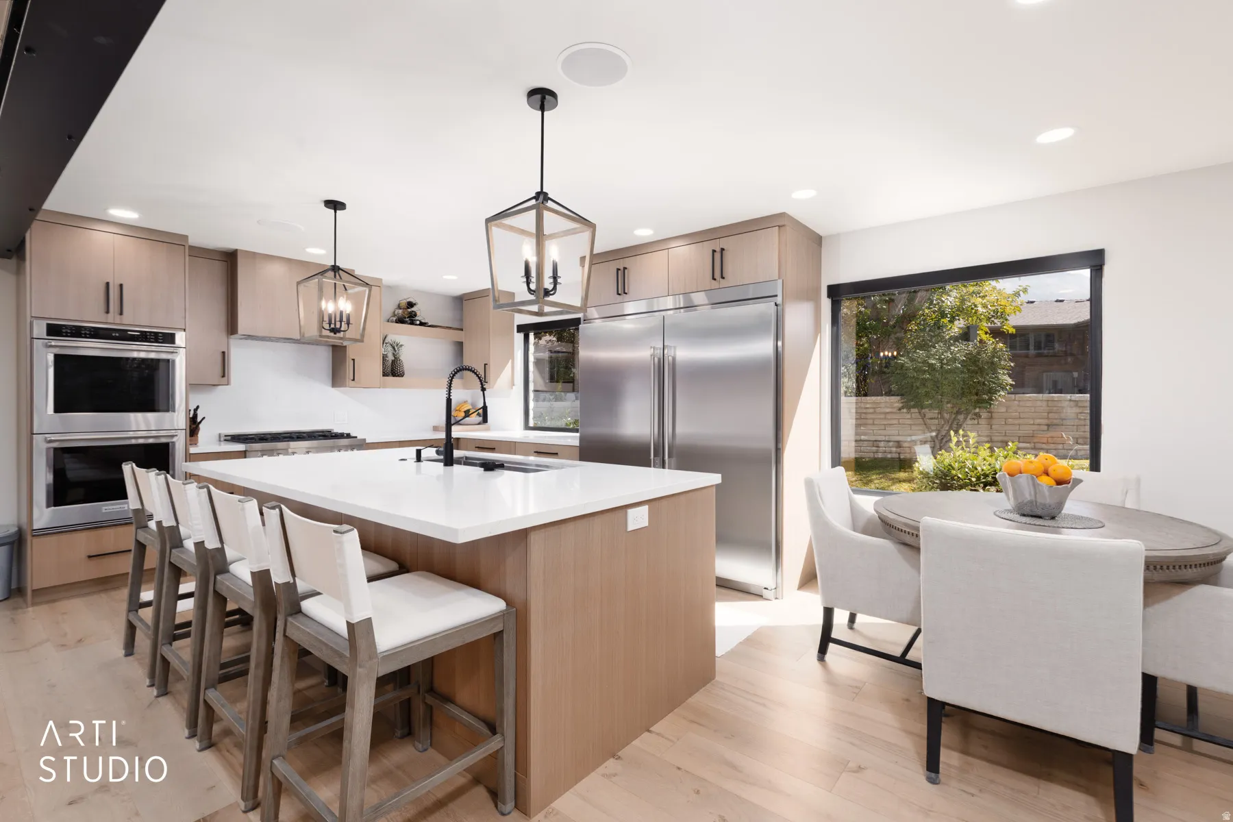Kitchen featuring light wood-finish cabinetry, stainless steel appliances, a center island with countertop seating, recessed lighting, and wood-finish flooring