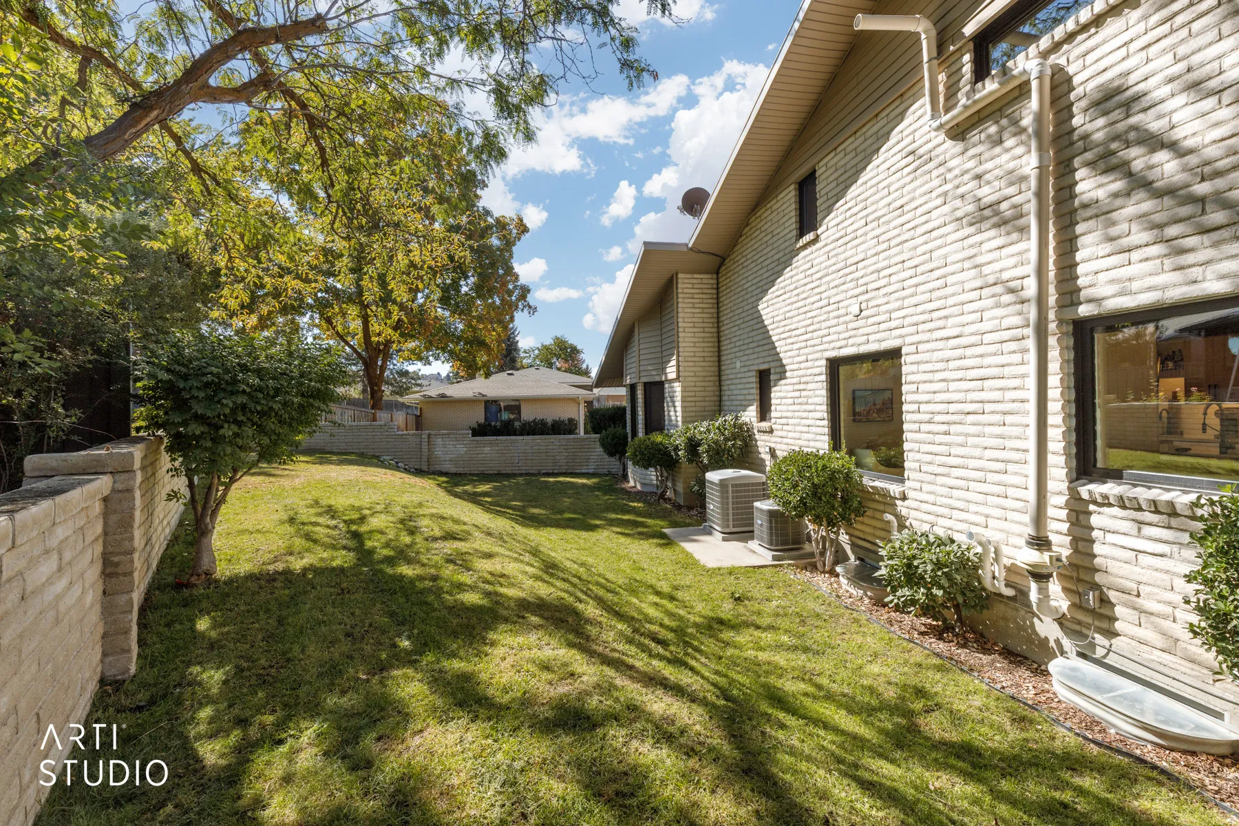Brick exterior with multiple windows and a sloped lawn