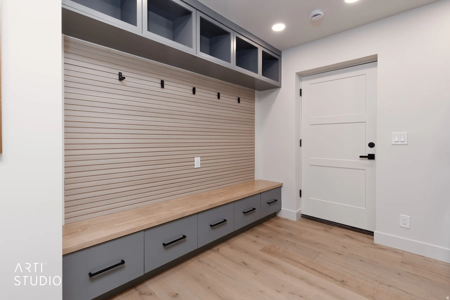 Built-in storage bench with gray cabinetry, wood-finish countertop, and integrated hooks