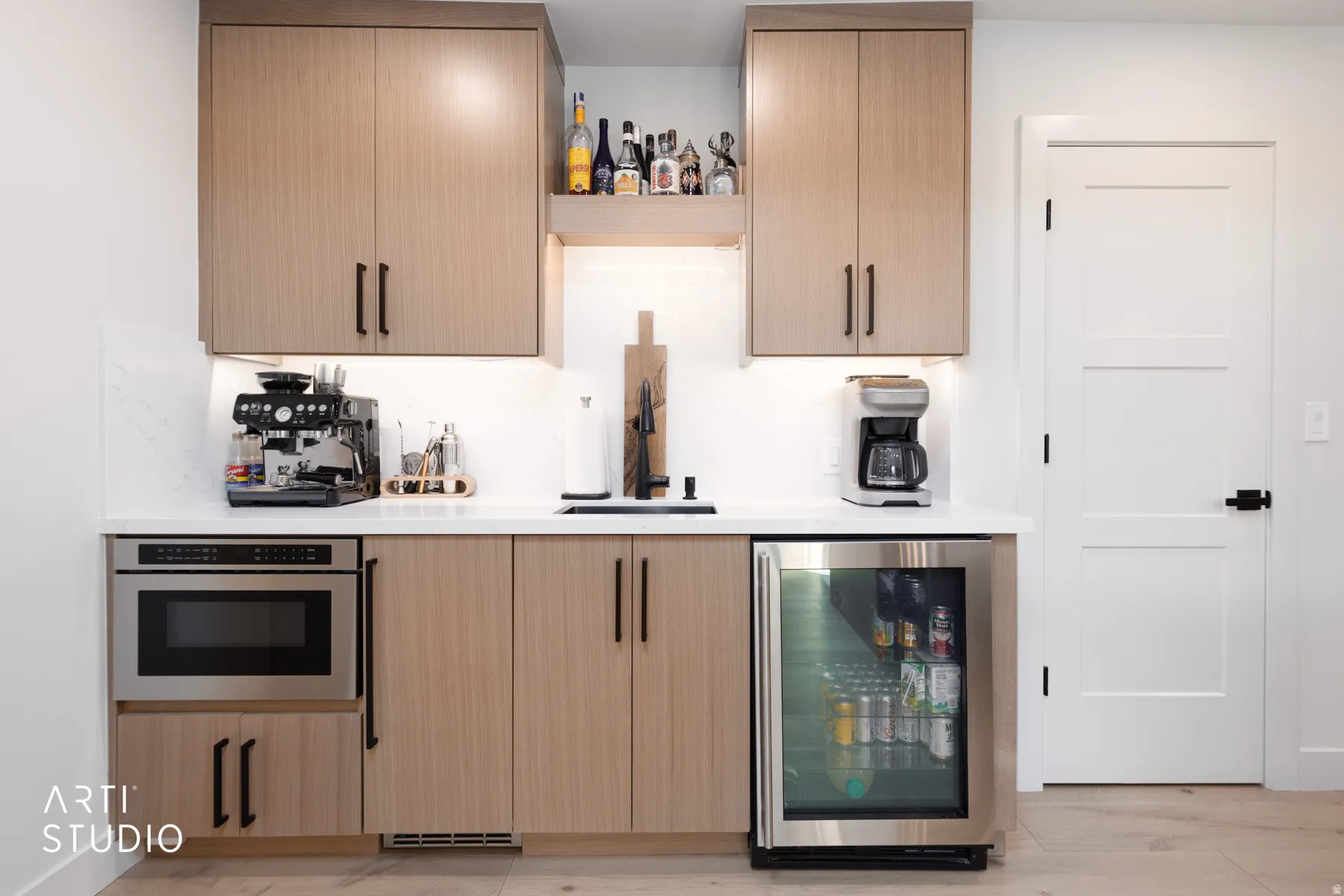 Integrated stainless steel microwave, beverage refrigerator, and sink with a matte black faucet