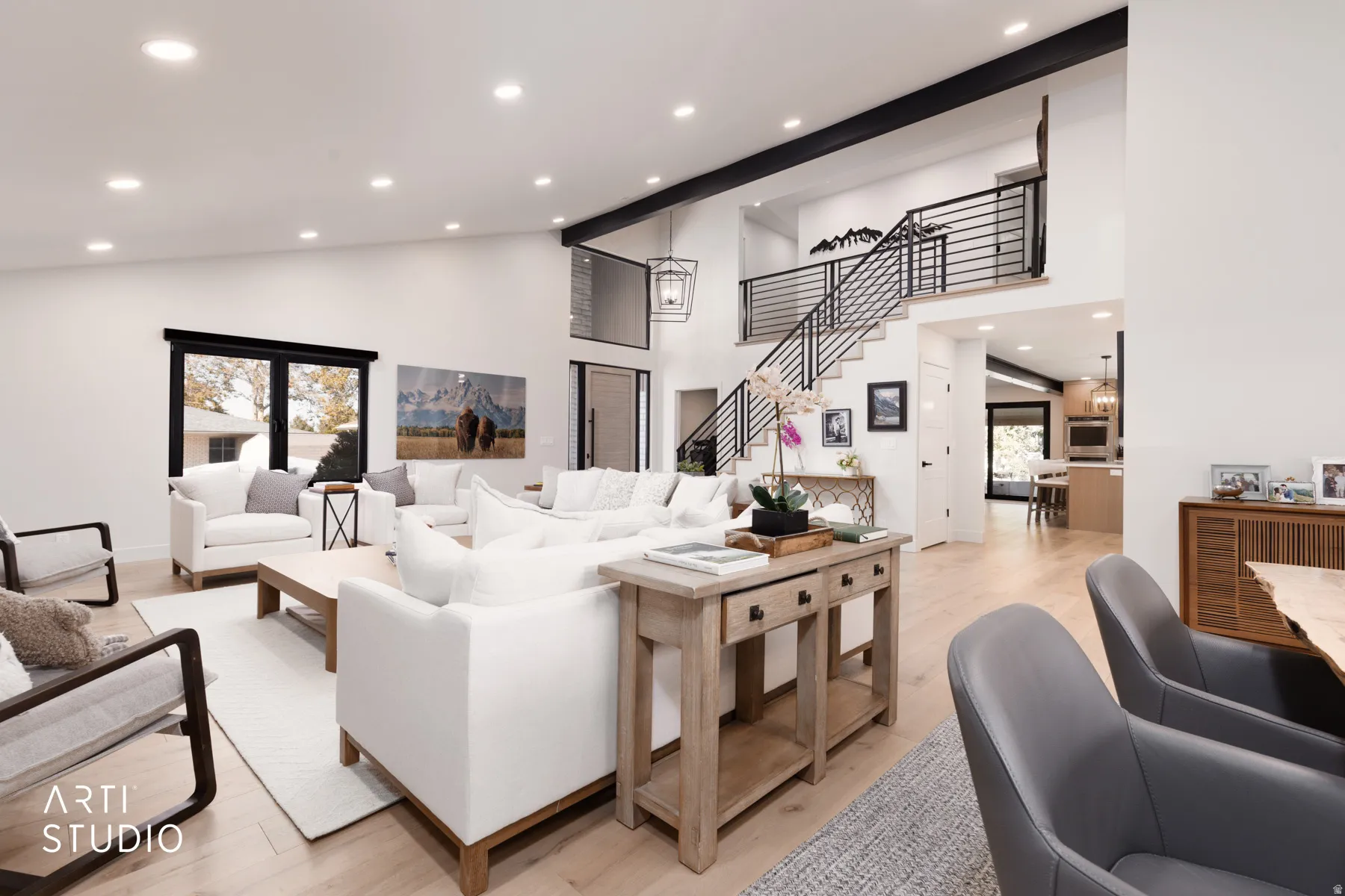 Spacious living area featuring high ceilings, wood-finish flooring, and a contemporary staircase with horizontal metal railings