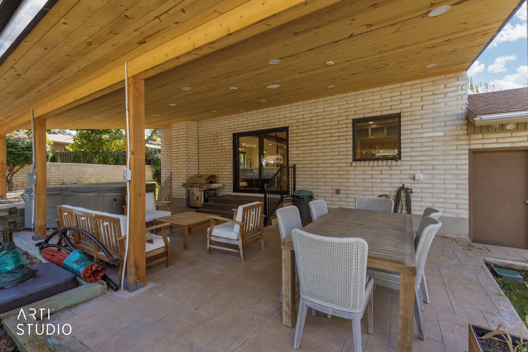 Covered patio featuring a wood-plank ceiling with recessed lighting, brick exterior wall, hot tub, and a built-in barbecue grill