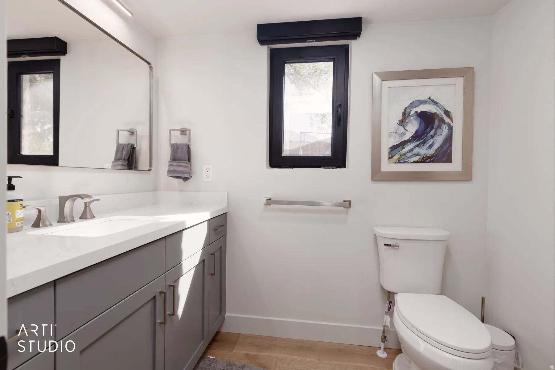 Vanity with a light-toned countertop, dual-handle faucet, and gray cabinetry