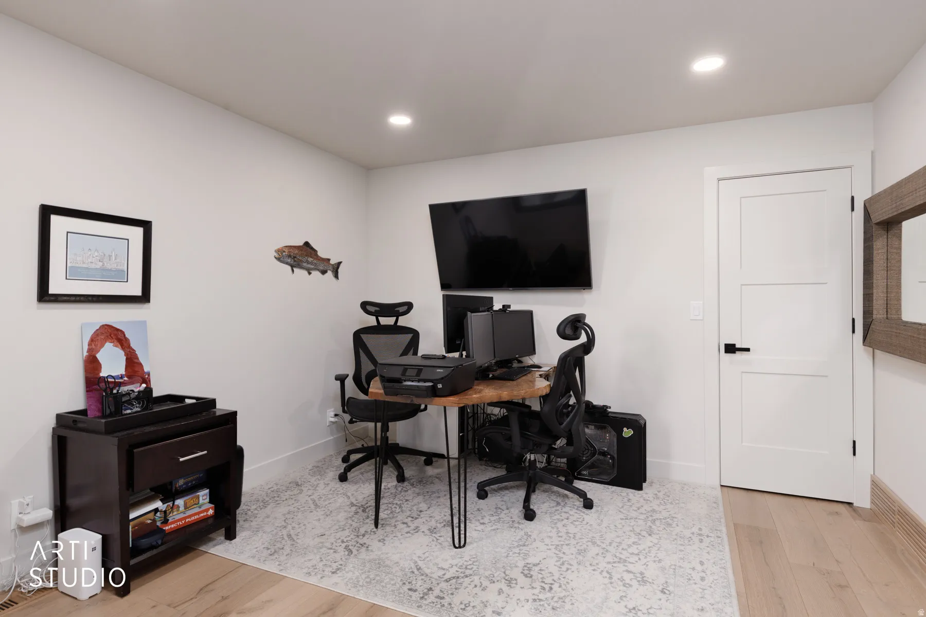 Recessed lighting, light wood-finish flooring, white walls, and a contemporary three-panel door with matte black hardware