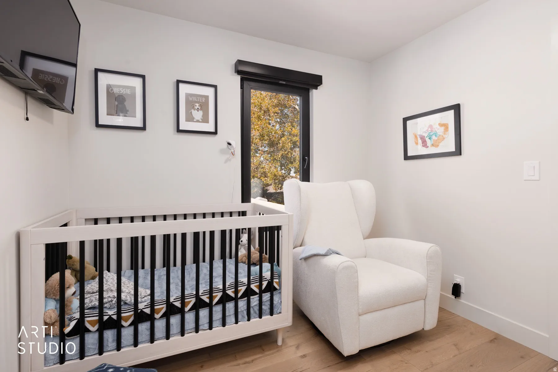 Wood-finish flooring with crisp white walls and a large window featuring a dark frame