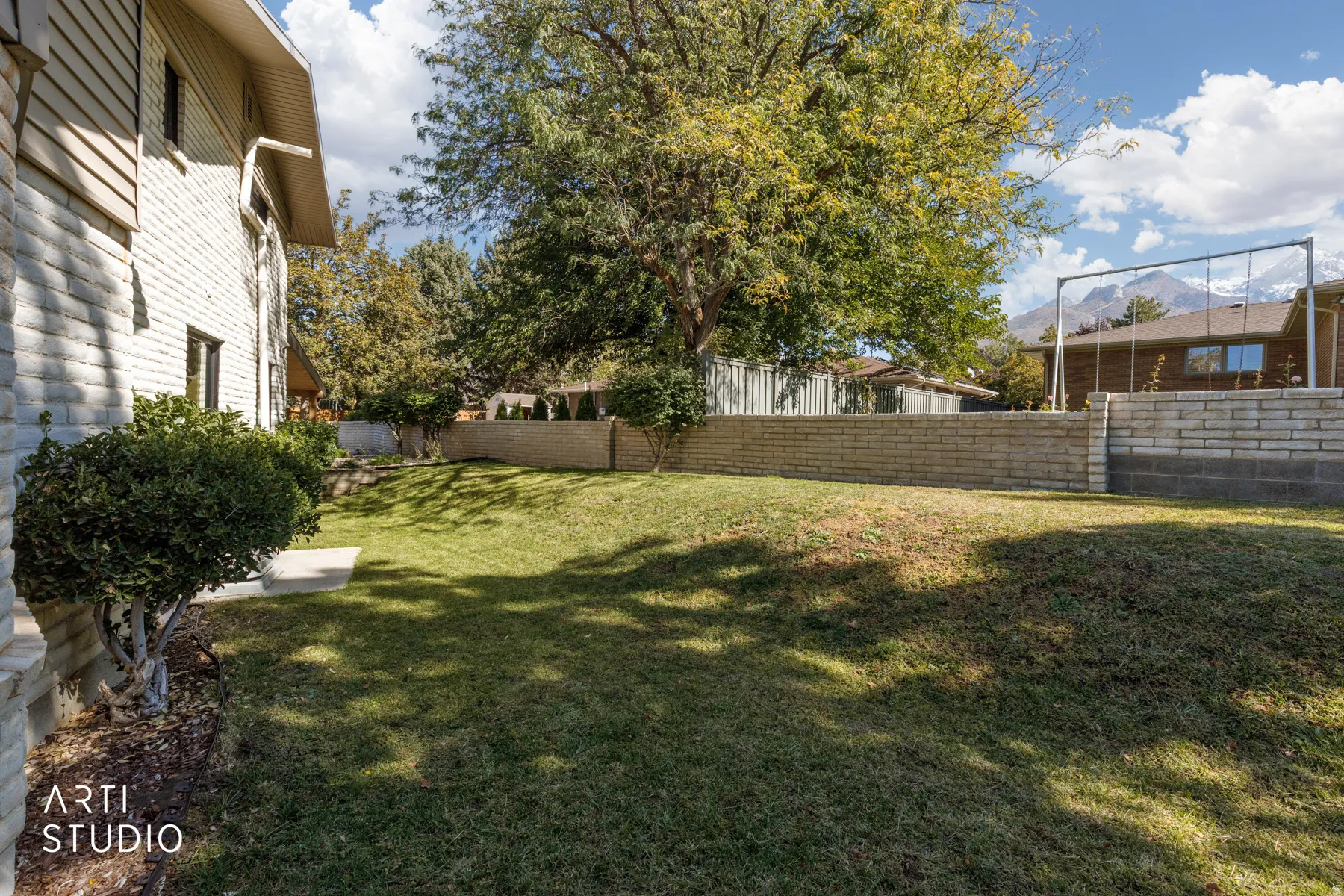 Expansive lawn area, mature trees, and a retaining wall