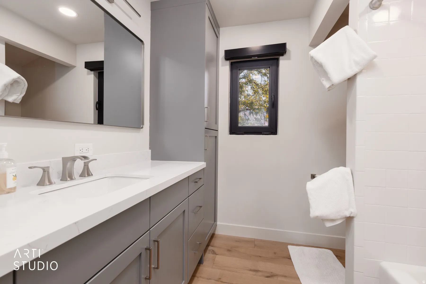 Modern bathroom featuring a single vanity with grey cabinetry, a light-colored countertop, and sleek brushed nickel fixtures