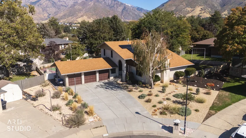 Property featuring a three-car garage, concrete driveway, and xeriscaped front yard with decorative rocks and plantings