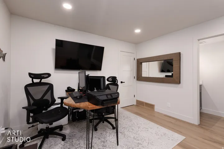Recessed ceiling lighting, light wood-finish flooring, white walls, and a white interior door with black hardware