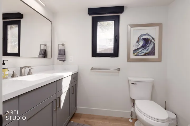 Vanity with a light-toned countertop, dual-handle faucet, and gray cabinetry
