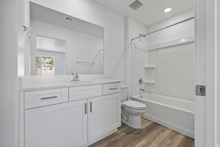 White vanity with chrome hardware, an integrated sink, and a large wall-mounted mirror