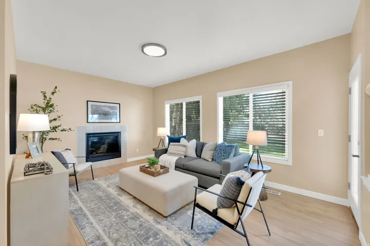 Living area featuring wood-finish flooring, a tiled fireplace, and multiple windows
