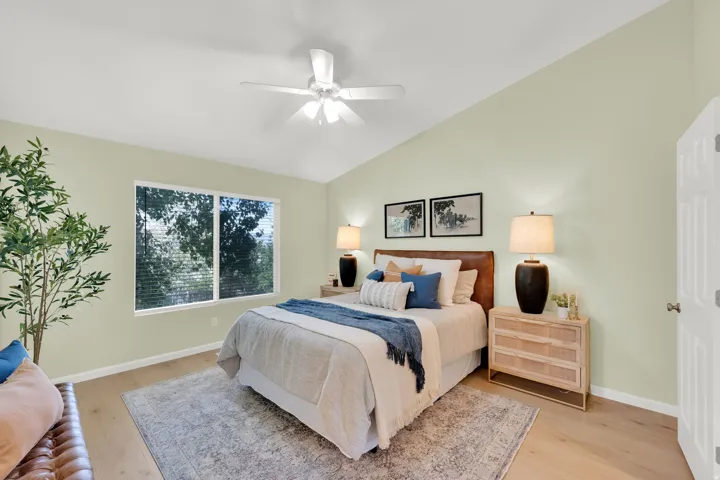 Vaulted ceiling with a ceiling fan, wood-finish flooring, and large windows with horizontal blinds
