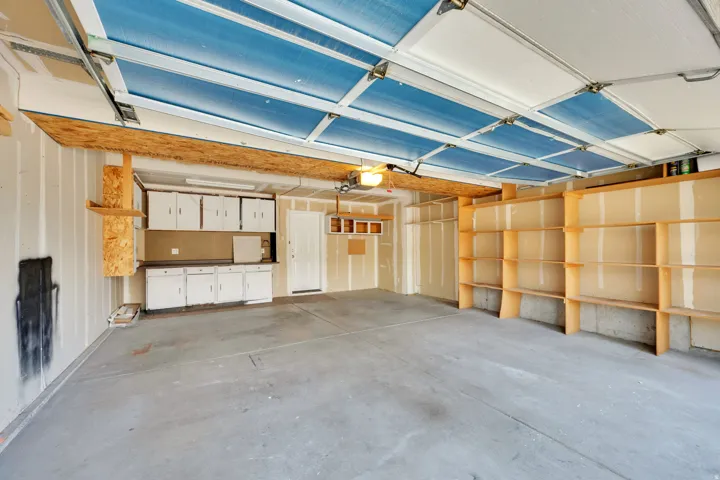 Attached garage with concrete flooring, built-in shelving, built-in cabinetry, and a ceiling-mounted light fixture