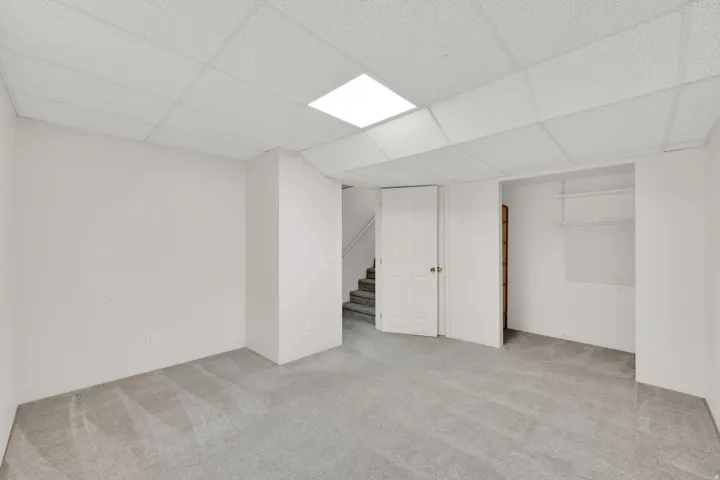 Recessed lighting, drop ceiling, wall-to-wall carpeting, open doorway, built-in shelving