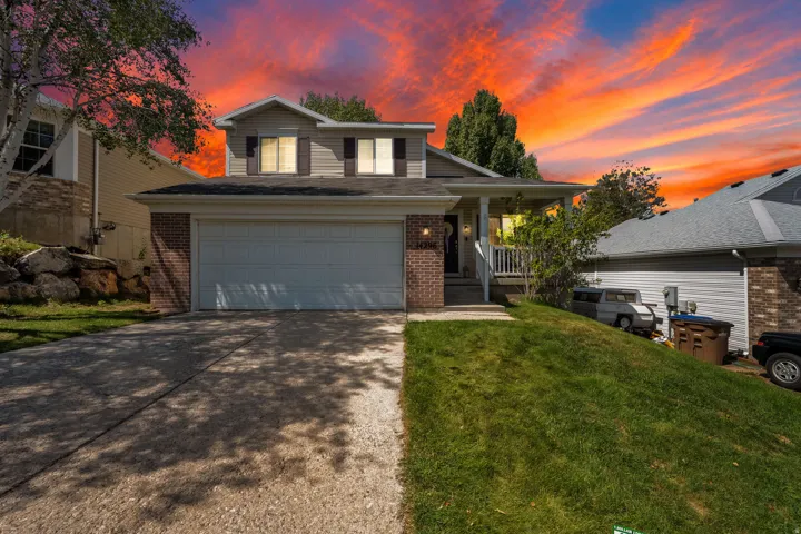 Two-story residence featuring a brick and siding exterior, an attached two-car garage, and a covered front porch