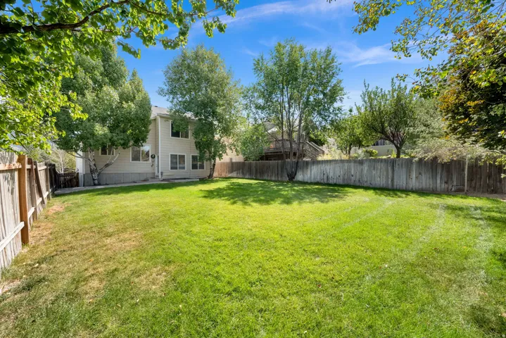 Expansive lawn area, mature trees, and a perimeter wood fence