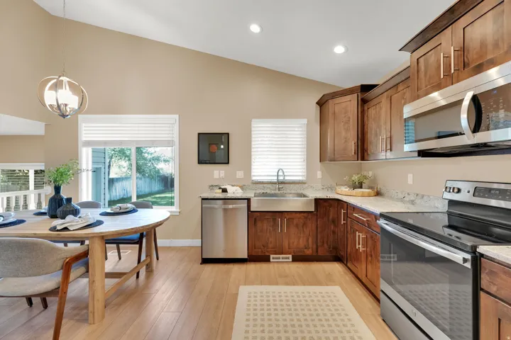Vaulted ceiling, wood-finish flooring, stainless steel appliances, wood cabinetry, and solid surface countertops