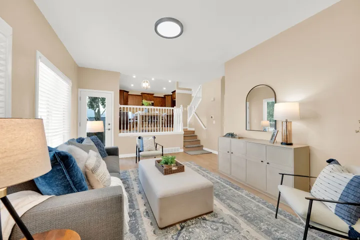 Open-concept living area featuring a neutral color palette, wood-finish flooring, and a white railing system