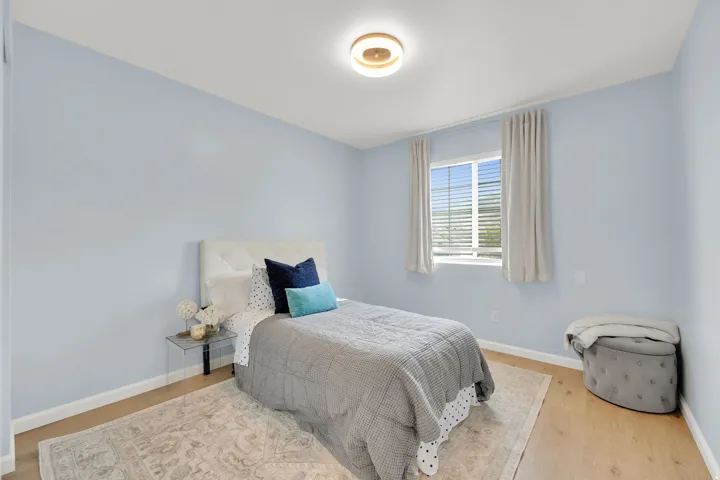 Light wood-finish flooring, a contemporary flush-mount ceiling light, and a window with blinds and drapes