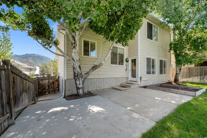 Two-story residence with horizontal siding, multiple windows, and a concrete patio