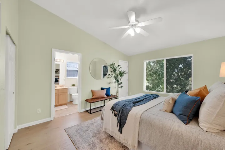 Vaulted ceiling with a ceiling fan, wood-finish flooring, and a large window