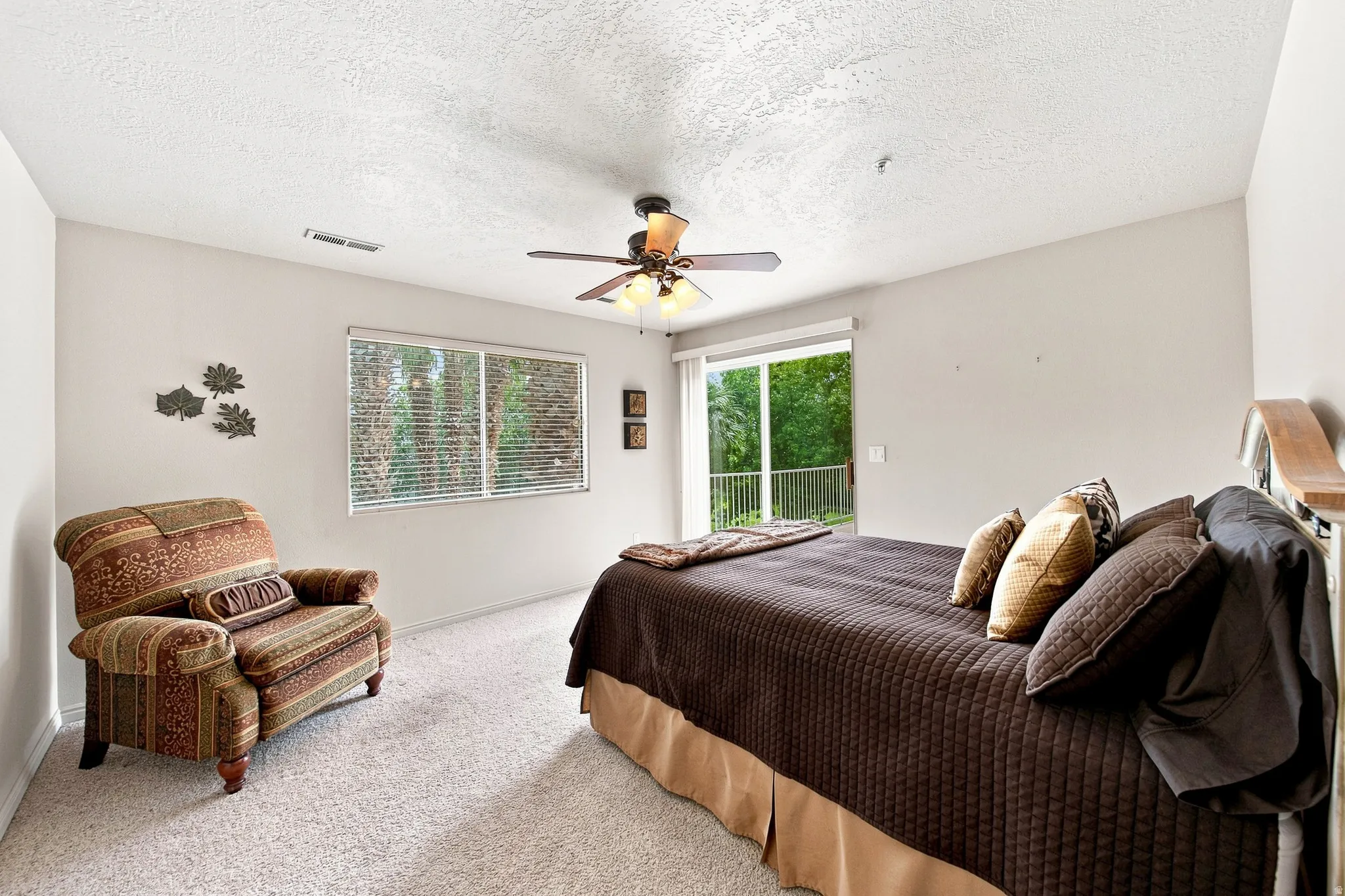 Neutral wall paint, textured ceiling, ceiling fan with integrated lighting, glass sliding door, and a permanent window with blinds