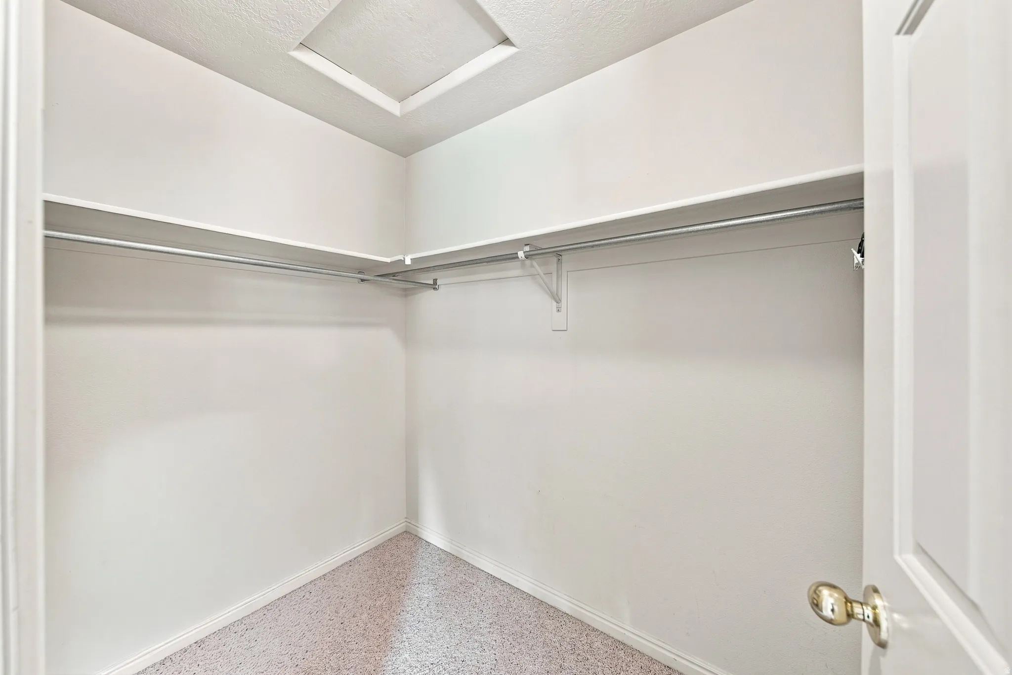 Walk-in closet featuring white walls, shelving, and hanging rods