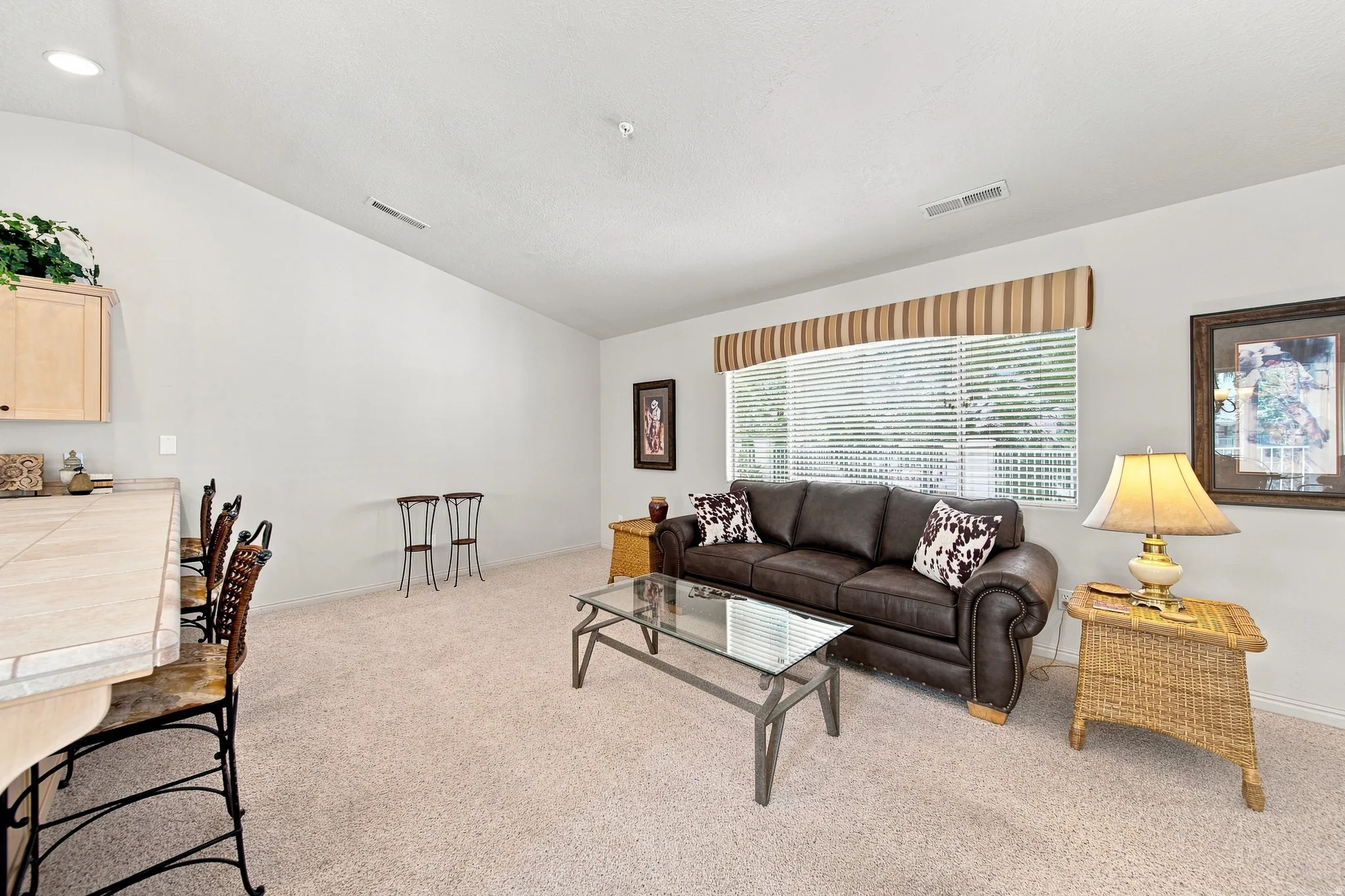 Vaulted ceiling, recessed lighting, expansive window with blinds, and light-toned carpeting