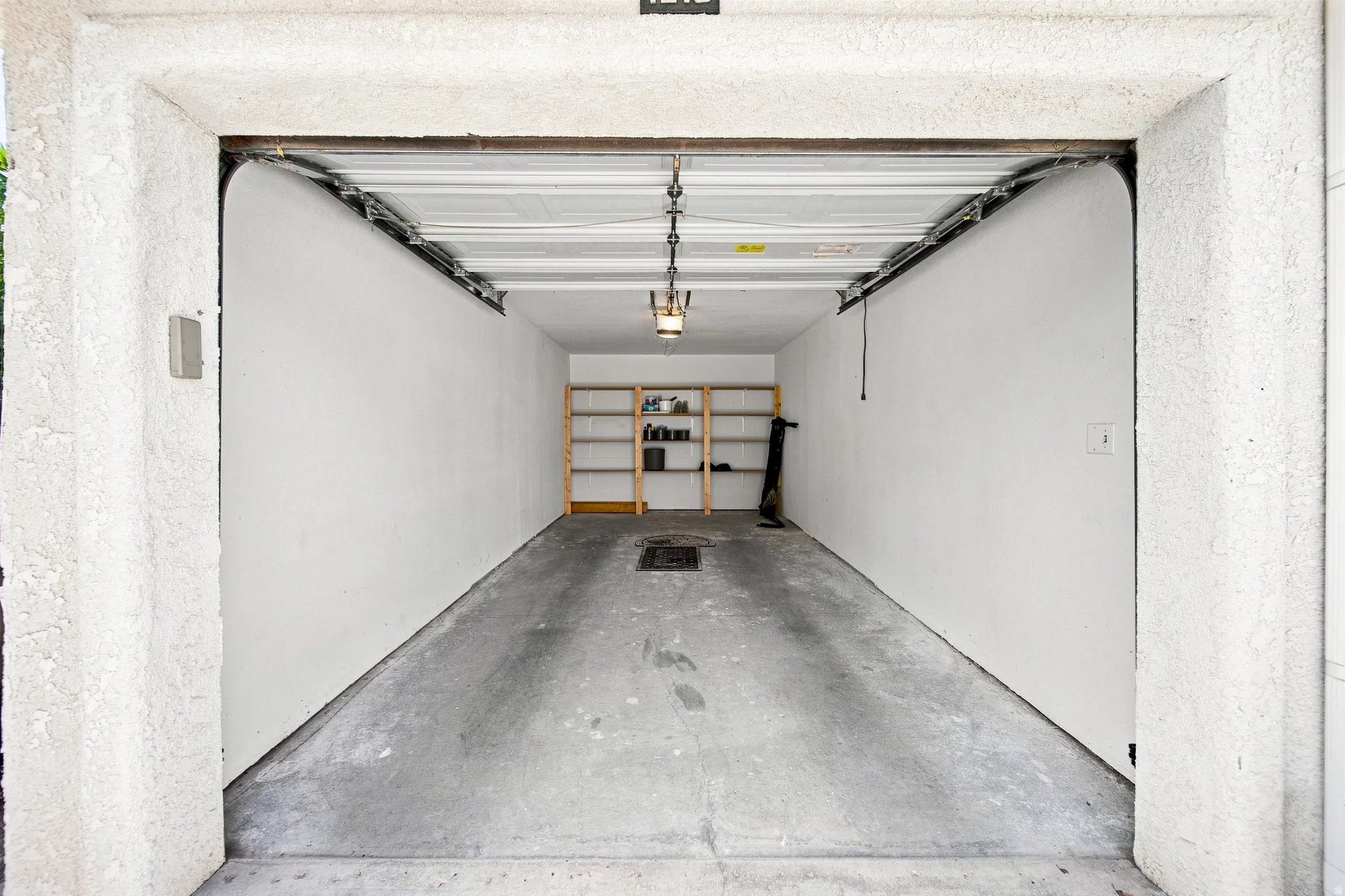 Garage space with concrete flooring, overhead lighting, and built-in shelving