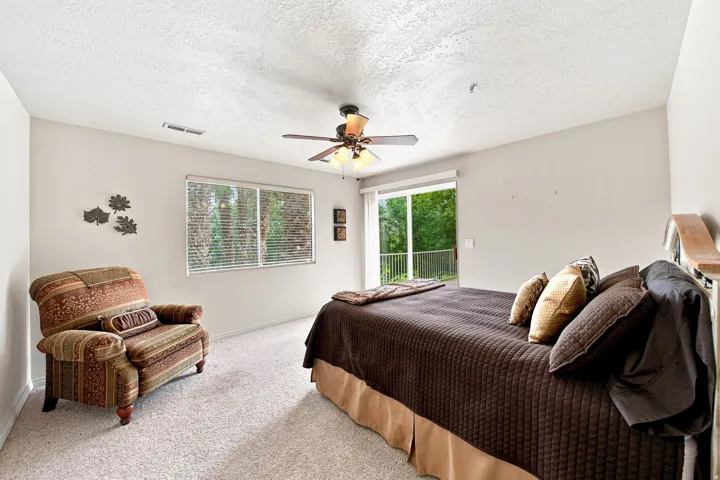 Neutral wall paint, textured ceiling, ceiling fan with integrated lighting, glass sliding door, and a permanent window with blinds