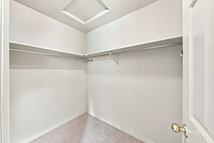 Walk-in closet featuring white walls, shelving, and hanging rods