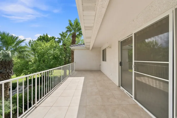 Private balcony featuring tile flooring, white railing, and sliding glass doors