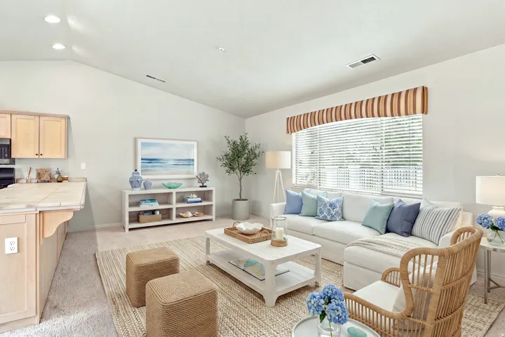 Vaulted ceiling with recessed lighting, large window with blinds, breakfast bar with tile countertop, light wood cabinetry, and carpeted flooring