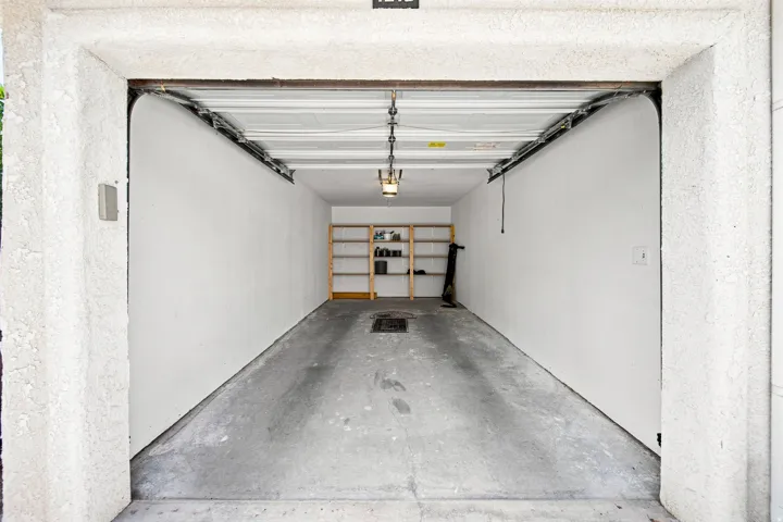 Garage space with concrete flooring, overhead lighting, and built-in shelving