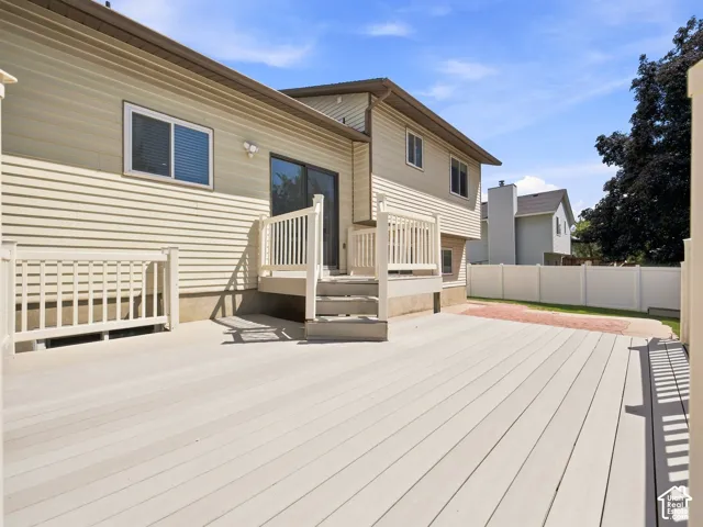 Expansive deck with light-toned composite decking, white railings, and direct access to the interior via a sliding glass door