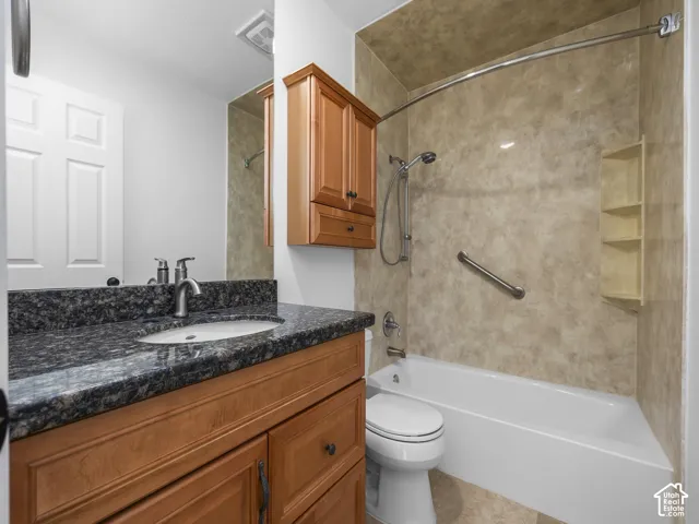 Bathroom featuring a wood-finish vanity with a dark speckled countertop, an integrated sink, and a combination tub and shower with a curved shower rod