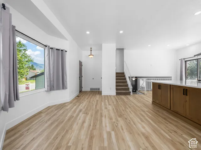 Expansive living space with wood-finish flooring, recessed lighting, and a prominent bay window