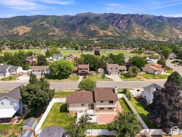 Mountain backdrop, residential neighborhood setting, fenced perimeter, paved patio area, pitched roofline
