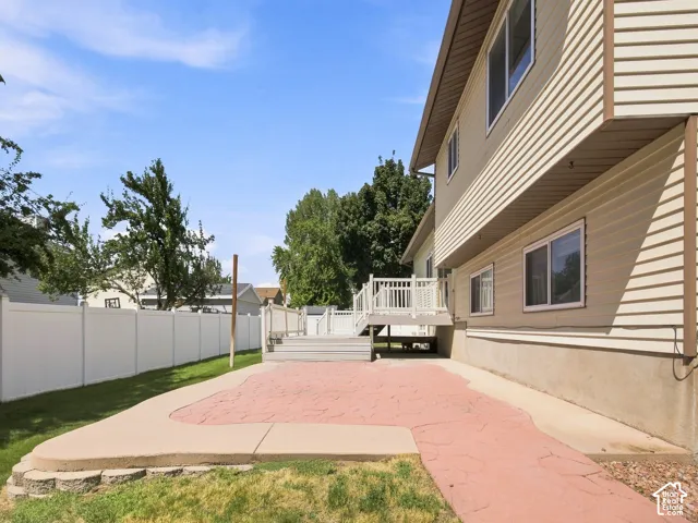 Expansive rear patio featuring a brick-paver surface with contrasting concrete border, backed by mature landscaping and privacy fencing