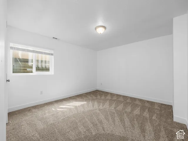 Bright secondary bedroom featuring neutral carpet flooring, recessed ceiling lighting, and a high-set window allowing natural light