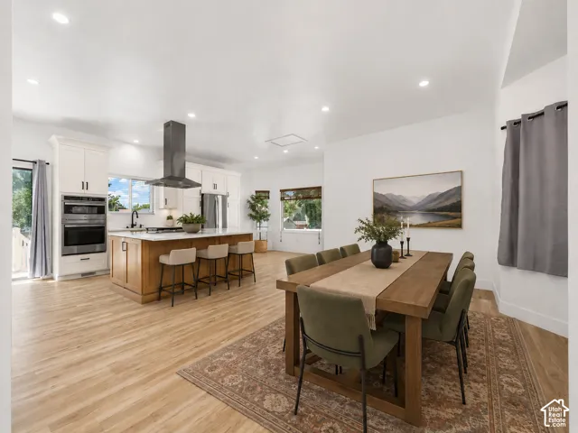 Kitchen featuring a large island with seating, double ovens, and a stainless steel range hood