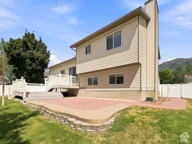 Two-story exterior with horizontal siding, featuring a multi-level deck, a ground-level patio, and a white privacy fence