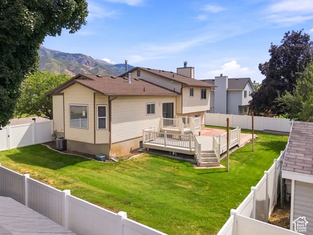 Spacious residential property featuring a cream-colored exterior with vinyl siding, covered front porch with white railings, and manicured lawn surrounded by white vinyl fencing
