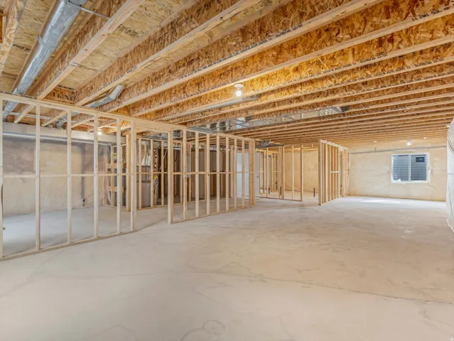 Framed interior walls with exposed wood ceiling beams, concrete flooring, and an egress window