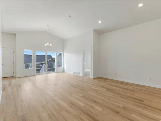 Vaulted ceiling with a central chandelier, wood-finish flooring, recessed lighting, and white walls