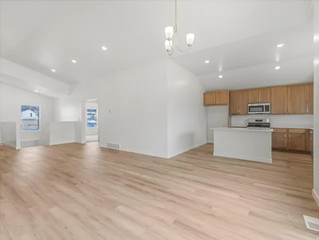 Open-concept main living area with wood-finish flooring, vaulted ceilings, and recessed lighting